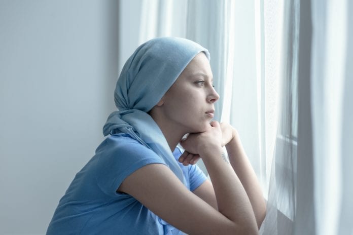 woman with cancer stares out hospital window