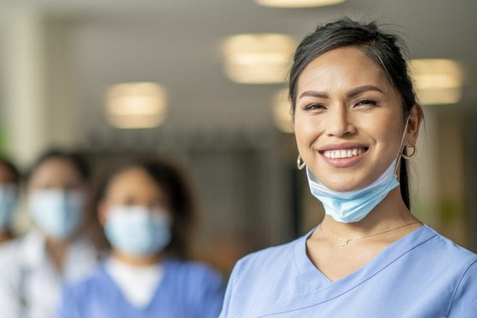 diverse group of masked nurses with woman nurse smiling in front