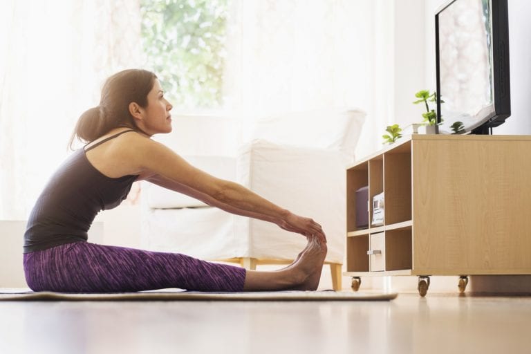 woman stretching at home in front of tv