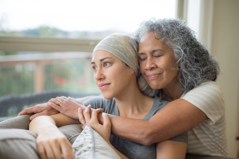 older parent embracing adult daughter with cancer