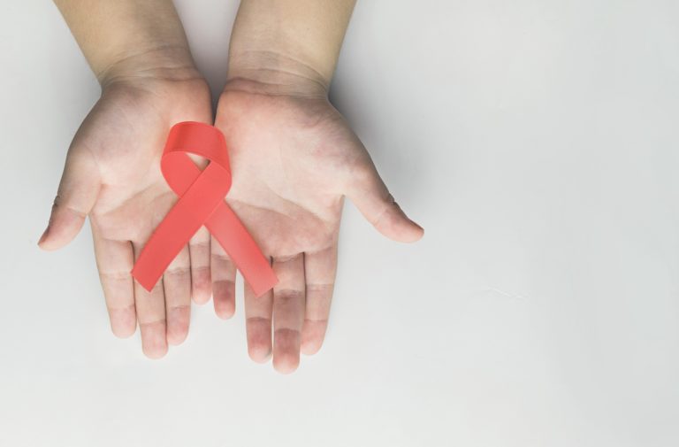 teen hands holding red hiv aids awareness ribbon