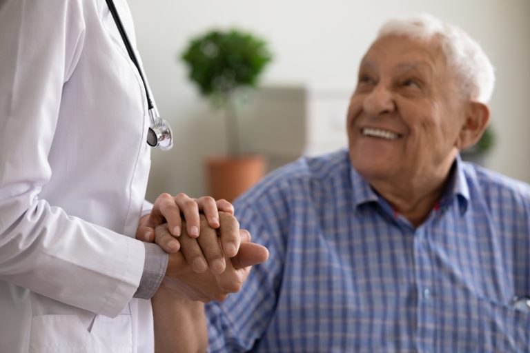 physician holds hand of geriatric patient
