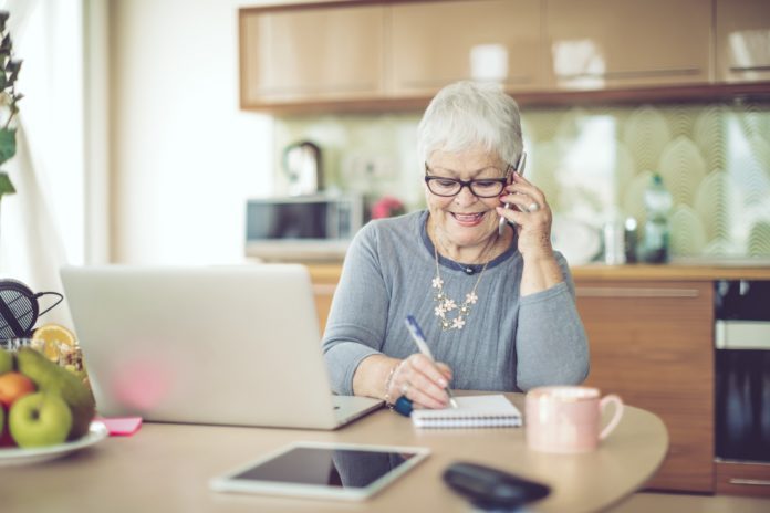 senior woman on phone in front of laptop