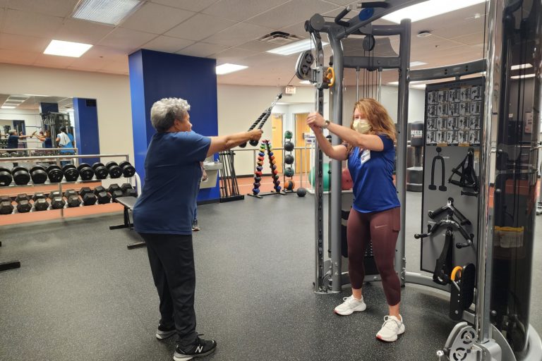 elderly woman and trainer strength training arms at emory decatur hospital wellness center