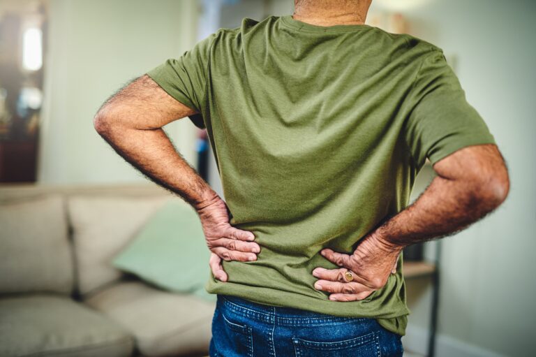 man with back pain holding lower back with both hands