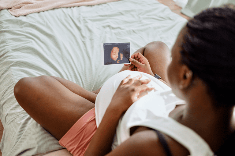 pregnant woman looks at ultrasound picture of baby