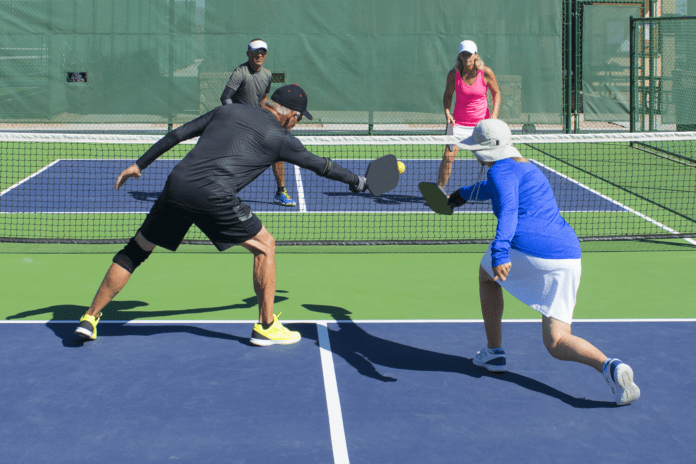 older adults play mixed couples pickleball on court