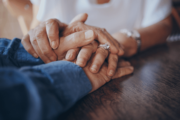 embracing hands of elderly couple