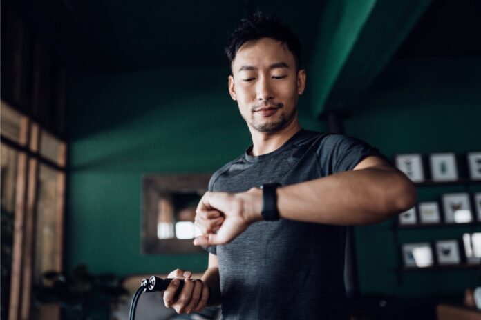 man monitors heart rate on wrist device while exercising